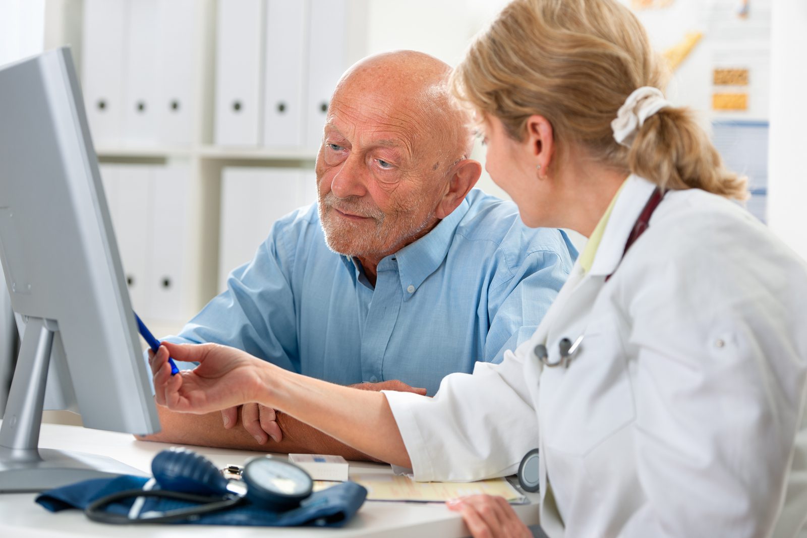 Healthcare professional explaining patient assessment data on screen in clinical office.