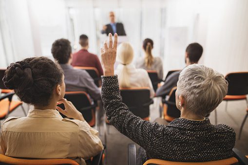 Group of people attending a Paul Wright professional event with one participant asking a question.