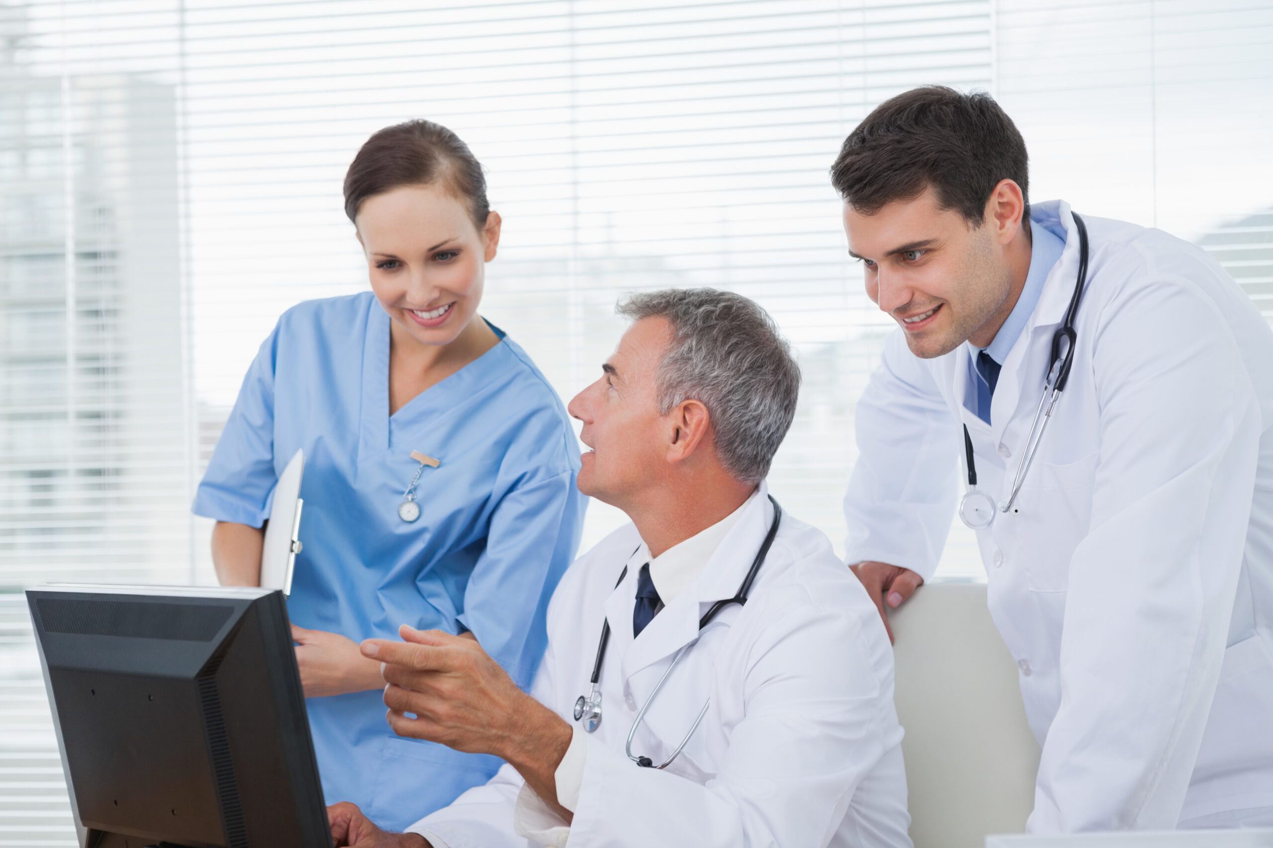 Team of healthcare professionals reviewing patient information on EMR software.