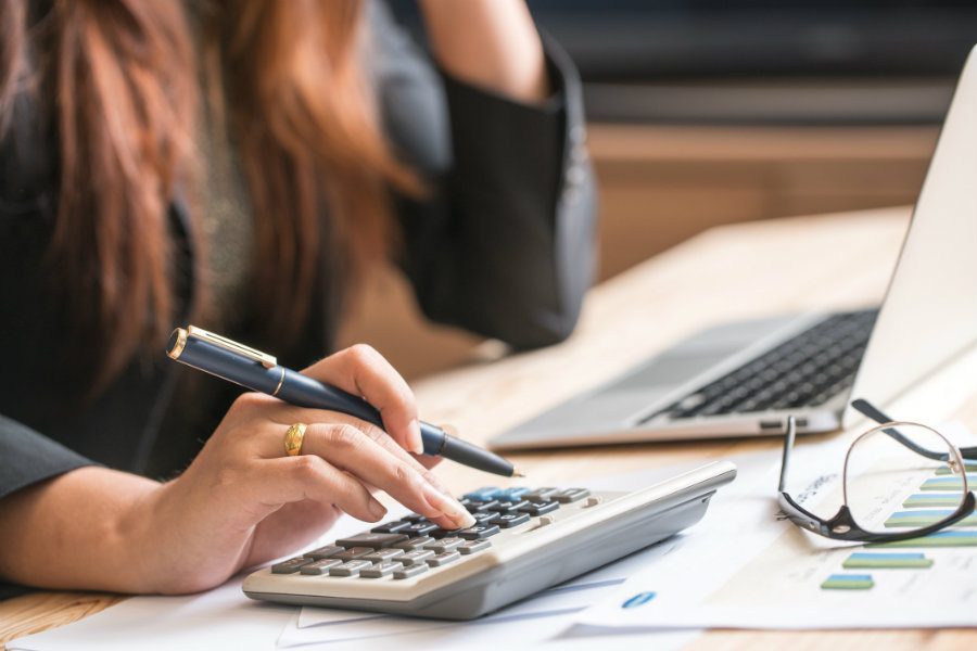 Close-up of business professional reviewing financial data and reports with a calculator and documents.
