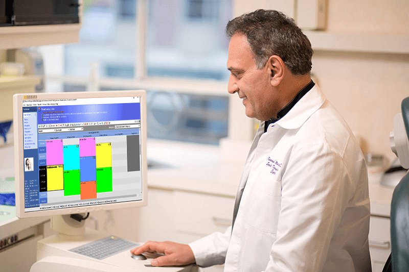 Doctor using practice management software on a computer to organize patient schedules.