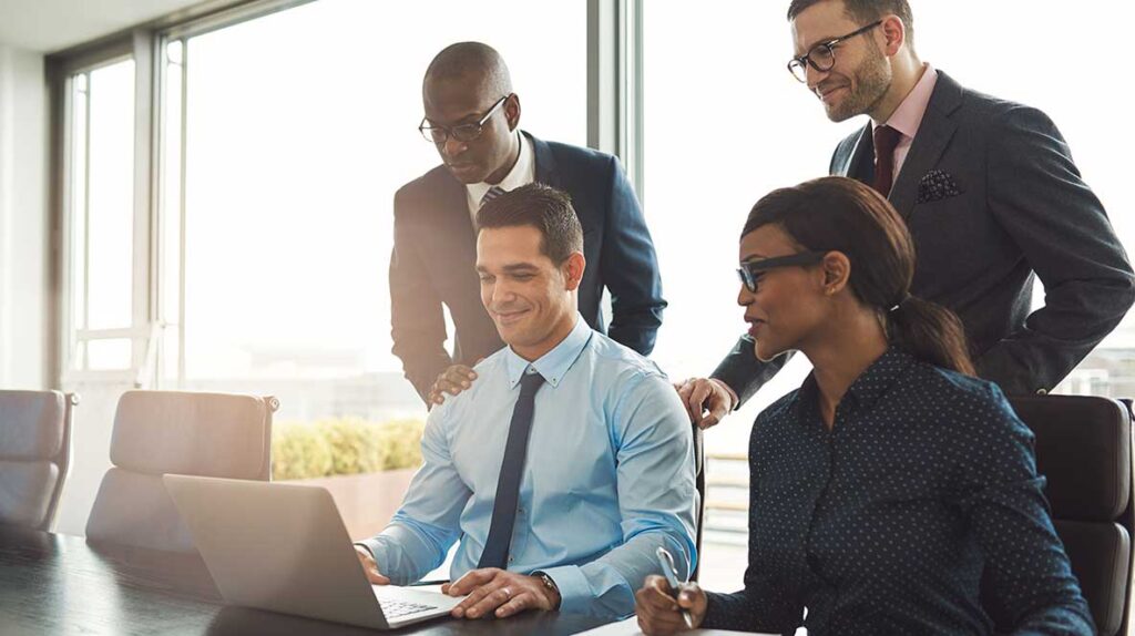 Business team reviewing practice management software performance on a laptop in a modern office.