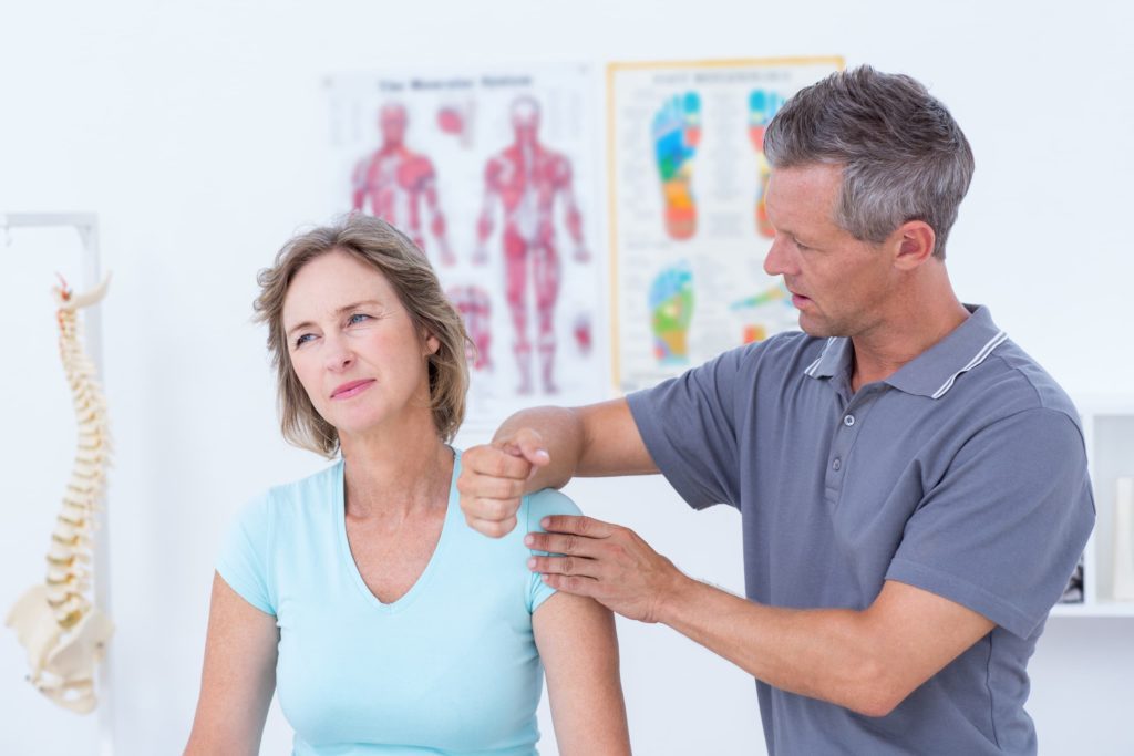 Physiotherapist examining patient’s shoulder pain during physical therapy session.