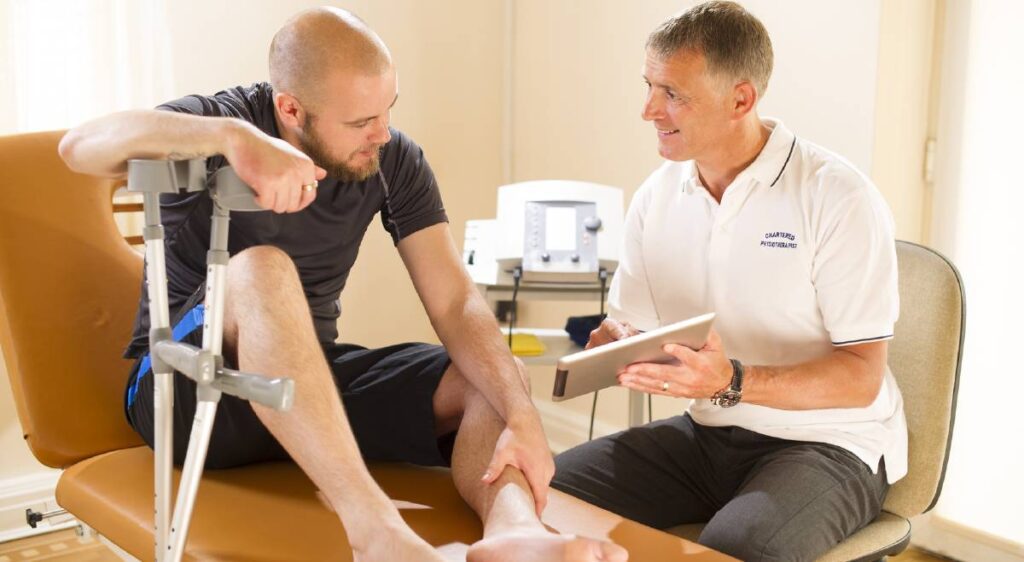 Physical therapist discussing digital medical records with patient using tablet.