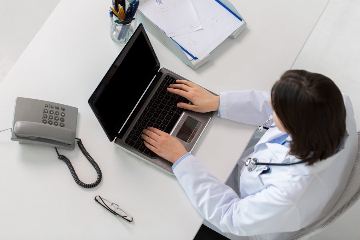 Doctor using electronic medical records software on computer in clinic.