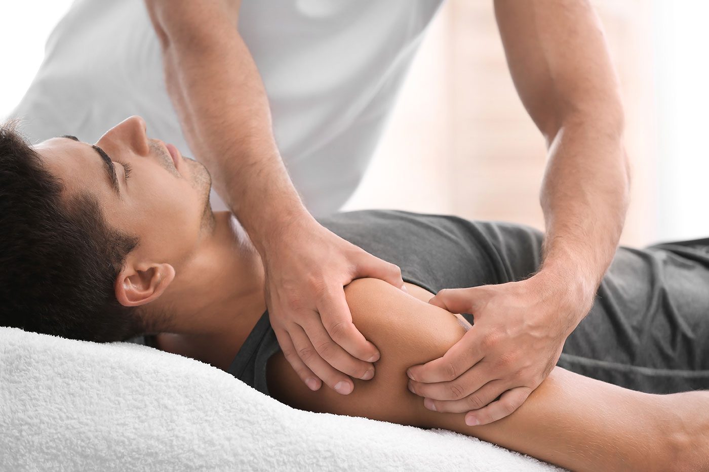 Physical therapist performing shoulder mobilization on a patient during treatment.