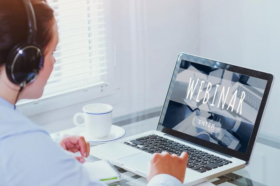 Healthcare professional attending a live online webinar on laptop for continued education.