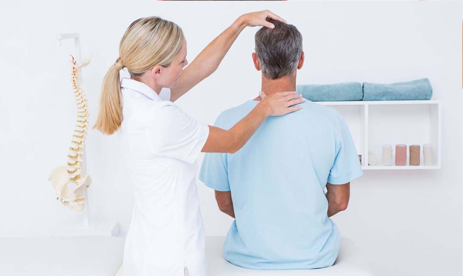 Physiotherapist performing neck assessment on male patient in clinic.