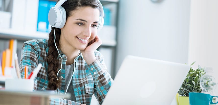 Smiling woman wearing headphones watching a webinar on her laptop.
